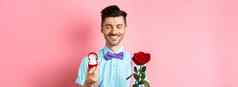 情人节一天可爱的的男朋友使婚礼建议显示订婚环小盒子红色的玫瑰表达爱站粉红色的背景