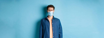 科维德医疗保健概念失望的家伙医疗面具皱着眉头困惑站蓝色的背景