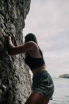 体育女人攀爬岩石年轻的女人苗条的适合身体