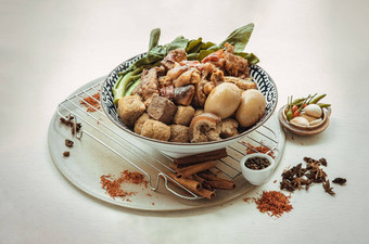 红烧猪肉腿煮熟的鸡蛋豆腐甘蓝陶瓷碗服务大蒜guinea-peppers白色背景