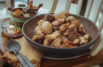 红烧猪肉腿煮熟的鸡蛋豆腐陶瓷碗服务勺子叉木背景