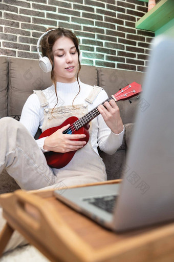 微笑女人记录内容视频博客玩尤克里里琴吉他解释了玩网络摄像头坐着沙发上首页封锁检疫在线培训爱好
