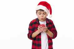 迷人的13岁以下的男孩红色的网纹衬衫圣诞老人他使珍惜圣诞节吹蜡烛