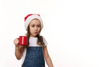 淘气的有趣的婴儿女孩圣诞老人他喝热可可喝吃棉花糖孤立的白色背景