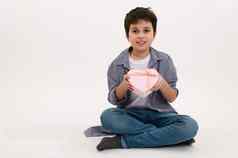 可爱的中东十几岁的男孩持有美丽的粉红色的心形状的礼物盒子孤立的白色背景