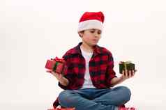 可爱的13岁以下的男孩穿圣诞老人他持有可爱的圣诞节礼物孤立的肖像白色背景复制空间