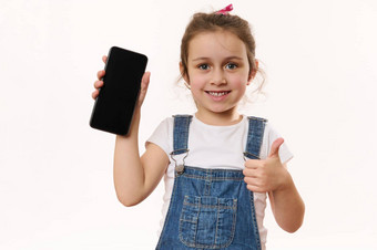 可爱的婴儿女孩持有智能手机空白屏幕复制空间促销文本微笑显示拇指相机