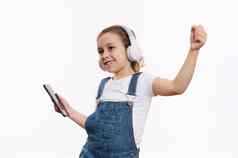 快乐的女孩智能手机听音乐立体声耳机孤立的白色背景复制空间