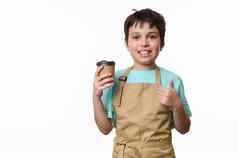 孤立的肖像白色背景快乐十几岁的男孩酒保显示拇指销售外卖咖啡纸板杯