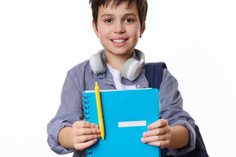 聪明的男孩主学校学生持有蓝色的字帖黄色的笔微笑相机教育概念