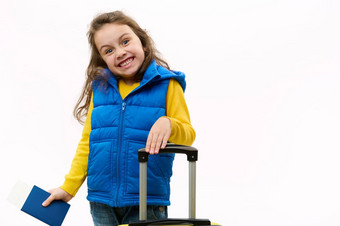 淘气的女孩黄色的毛衣蓝色的夹克提出了登机通过手提箱白色背景