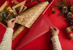 前视图女人的手滚动红色的礼物纸鹿模式包装包装圣诞节礼物