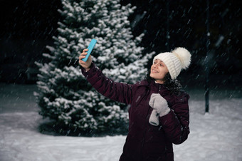 多民族漂亮的女人温暖的衣服微笑采取自拍智能手机享受雪冬天晚上