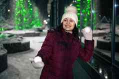 快乐年轻的女人穿温暖的衣服白色羊毛他连指手套玩雪球打架雪冬天晚上