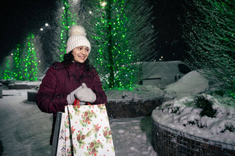 愉快的女人购物袋走街减轻了节日照明冬天雪晚上