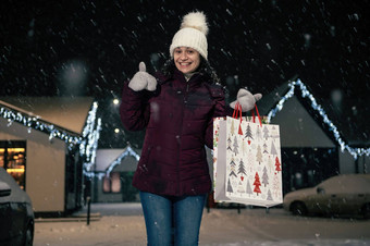 迷人的女人经历幸福显示拇指微笑高高兴兴地相机街雪晚上