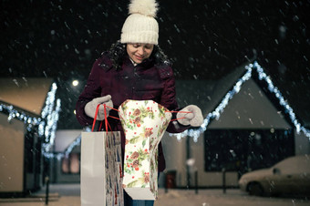 漂亮的女人购物袋走雪覆盖街雪冬天冷晚上