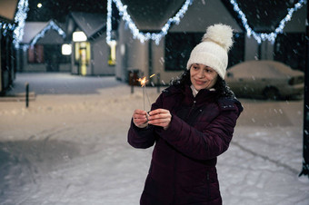 漂亮的女人照明罗马焰火筒孟加拉灯走城市街照亮花环雪晚上