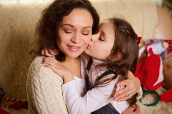 可爱的孩子可爱的婴儿女孩可爱的女儿拥抱接吻爱的妈妈。圣诞节首页室内