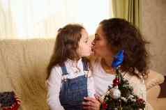 快乐家庭爱的妈妈。女儿接吻拥抱享受圣诞节准备工作首页