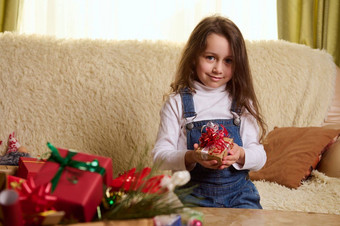 可爱的<strong>孩子</strong>女孩坐着沙发首页室内<strong>圣诞</strong>节礼物盒子手精明地微笑相机