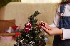 特写镜头儿童手圣诞节玩具闪亮的球装修圣诞节树12月一年准备工作