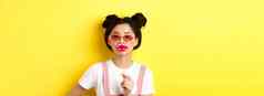 夏天时尚概念时尚的亚洲富有魅力的女孩太阳镜持有聚会，派对嘴唇面具站黄色的背景