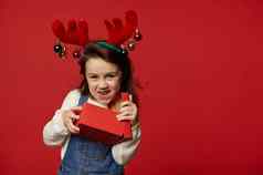 淘气的有趣的孩子女孩鹿鹿角希望拆包礼物盒子惊喜圣诞节红色的背景