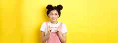 夏天生活方式概念可爱的害羞的亚洲女孩微笑愚蠢的避免眼睛联系站黄色的背景