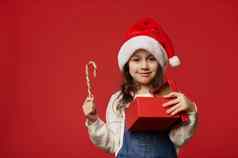 快乐女孩微笑相机持有糖果礼物盒子快乐圣诞节现在孤立的红色的背景