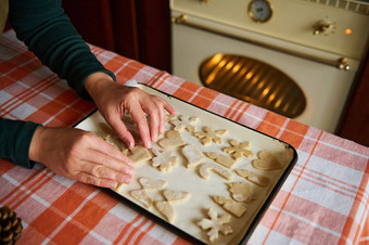 特写镜头女人的手把姜饼饼干烘焙表站表格加热烤箱