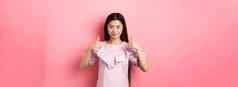 微笑亚洲女孩衣服显示拇指批准产品赞美伟大的交易站粉红色的背景