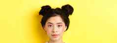 头肖像时尚的亚洲女孩明亮的化妆发髻相机站黄色的背景