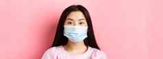 科维德健康的人概念特写镜头亚洲可爱的女孩穿医疗面具病毒爆发站粉红色的背景