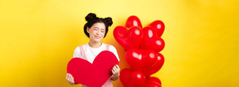 快乐情人节一天愚蠢的美丽的亚洲女人微笑梦幻显示红色的心成像浪漫的日期情人站黄色的背景