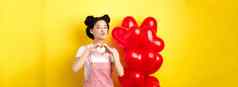 美丽的亚洲女人显示心爱手势接吻嘴唇站浪漫的红色的气球概念情人节一天