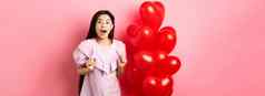 兴奋惊讶十几岁的朝鲜文女孩开放口惊讶收到惊喜礼物情人节一天想知道站心气球粉红色的背景