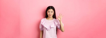 微笑亚洲女人衣服显示标志<strong>赞美赞美</strong>好事情批准优秀的选择站粉红色的背景