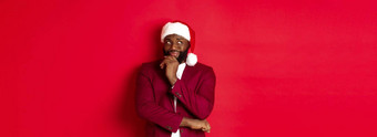 圣诞节聚会，派对假期概念微笑非洲美国男人。使一年计划深思熟虑的上左角落里穿圣诞老人他红色的背景