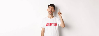 英俊的年轻的男人。志愿者t恤的想法提高手指建议白色背景