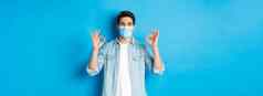 概念科维德流感大流行社会距离满意男人。医疗面具显示迹象批准同意好站蓝色的背景
