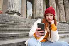 肖像年轻的红色头发的人女人复杂的脸坐在街楼梯红色的他持有智能手机皱眉深思熟虑的感觉不安
