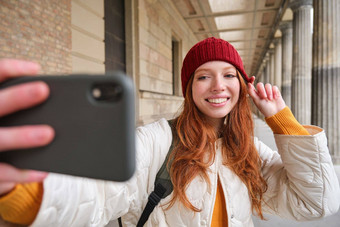 可爱的年轻的红色头发的人女人需要自拍街<strong>移动</strong>电话使照片智能手机应用程序街