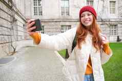 肖像快乐女孩旅游需要自拍智能手机前面历史建筑摆姿势照片移动电话相机