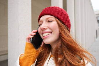 移动宽带人微笑年轻的红色头发的人女人走小镇会谈移动电话调用朋友智能手机互联网使调用在国外