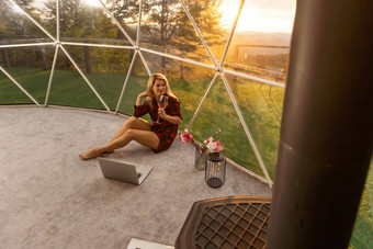 中间岁的女人移动PC休息支出时间豪华露营房子假期假期圆顶帐篷舒适的野营舒适生活方式概念