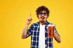 帕特里克一天年轻的啤酒节男人。服务大啤酒杯子喝孤立的黄色的背景的家伙显示标志手指