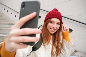 <strong>移动</strong>电话人生活方式时尚的红色头发的人女孩需要自拍智能手机提出了照片<strong>移动</strong>电话手微笑幸福的坐在楼梯在户外