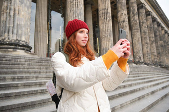 肖像年轻的博主红色头发的人女孩旅游需要图片观光使照片智能手机相机记录视频微笑