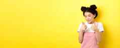 可爱的青少年亚洲女孩美化妆显示拇指微笑赞扬激励使赞美站很高兴黄色的背景